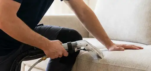 Professional upholstery cleaner deep-cleaning a fabric sofa with a handheld extraction tool, St Paul, MN.